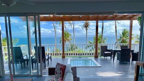 A spacious balcony with a pool, outdoor seating, and a view of the ocean.