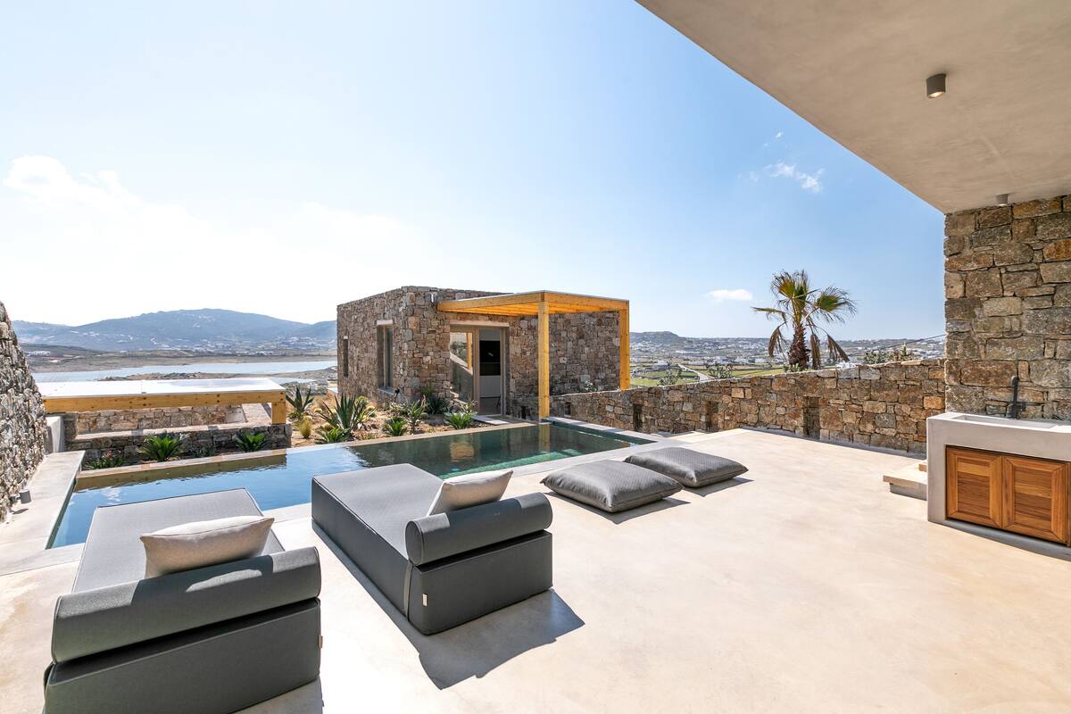 A modern outdoor pool area with built-in seating and a stone structure.