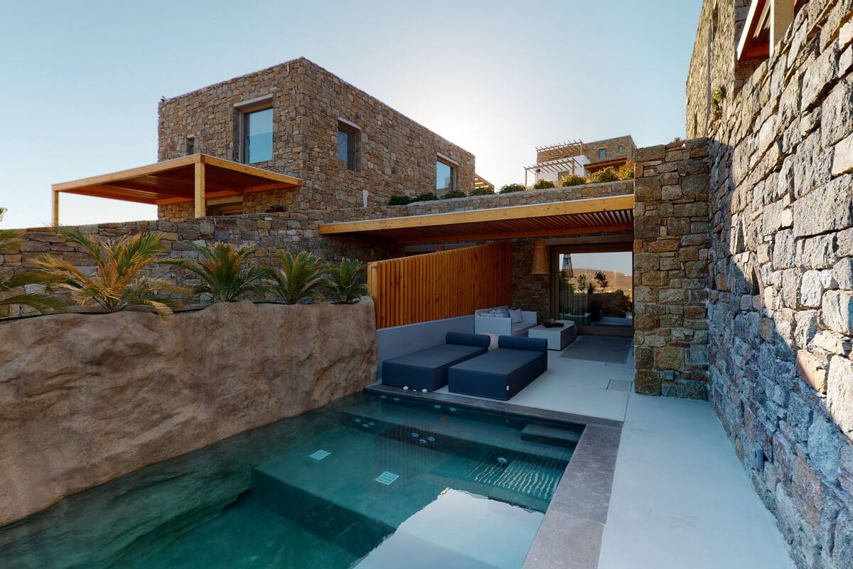 A modern house with a stone exterior, a swimming pool, and outdoor seating.