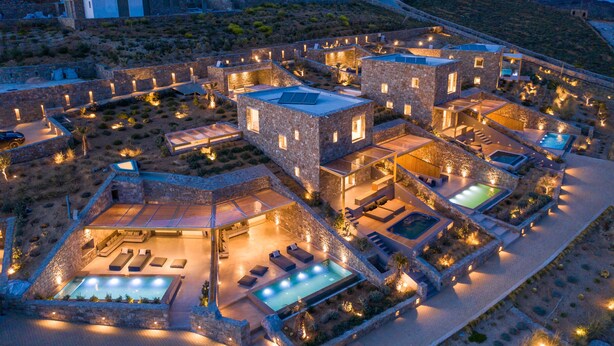 A luxurious resort with multiple swimming pools, outdoor seating areas, and stone architecture. - Panormos Bay Suites (Mykonos)