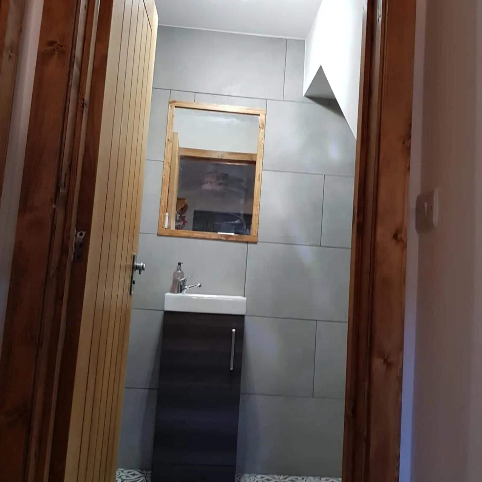 A bathroom with a wooden door, a mirror, a sink, and a window.