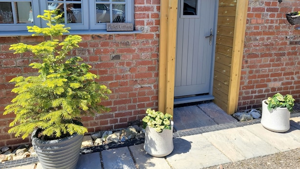 Un bâtiment en briques sur lequel est apposée une enseigne indiquant « Piglet Cottage ».