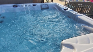 Un bain à remous avec jets d’eau, entouré d’une terrasse en bois et d’une clôture.