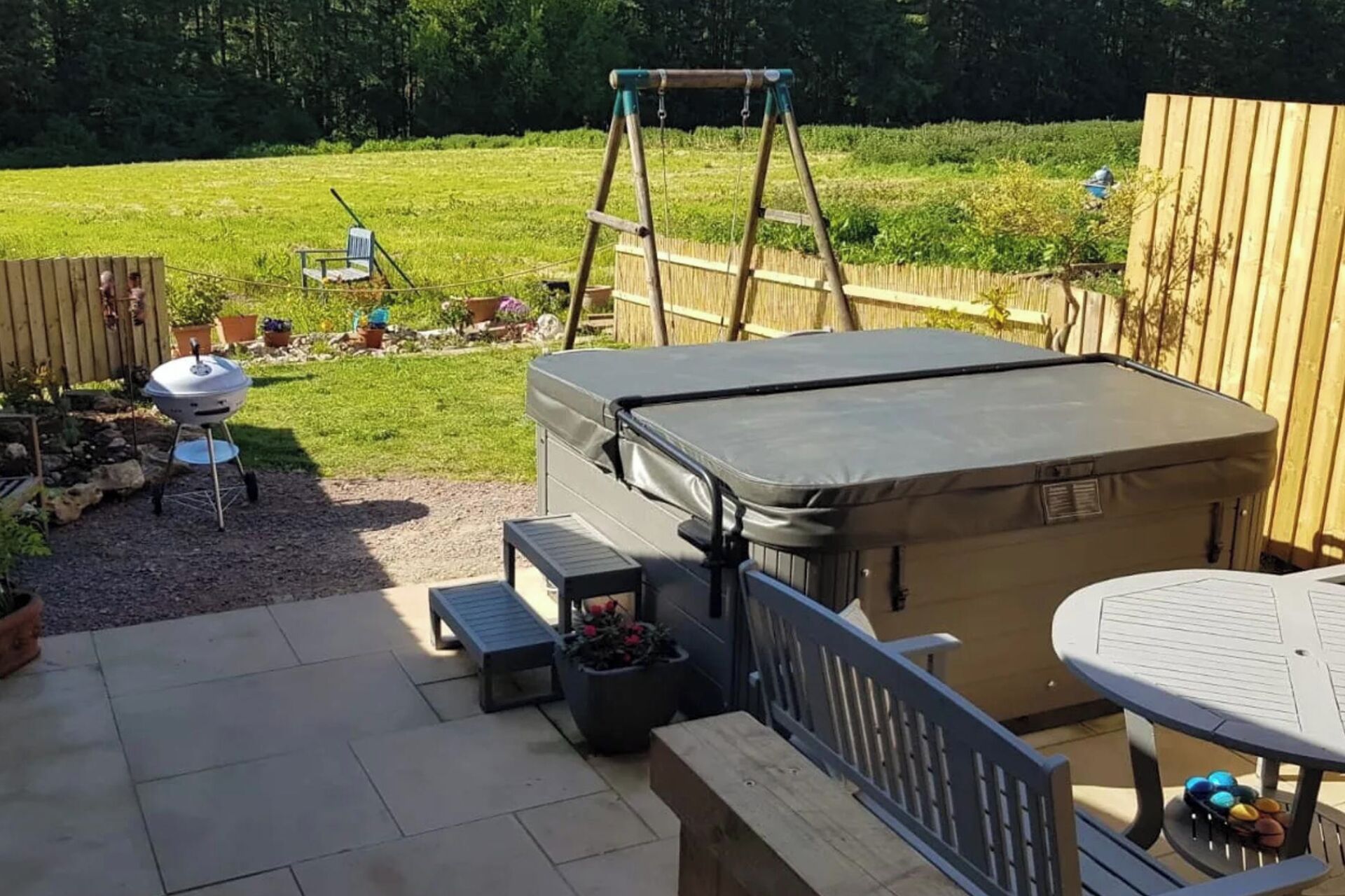 A backyard with a covered seating area, a barbecue grill, and a ladder.