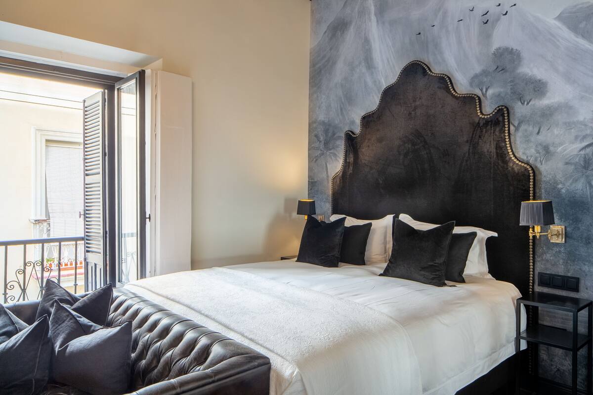 Un dormitorio con una cama grande, un cabecero de diseño único y vistas al balcón exterior.