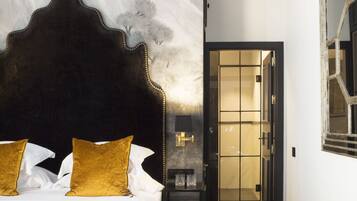 A hotel room with a large bed, a headboard, a nightstand, and a wall-mounted lamp.