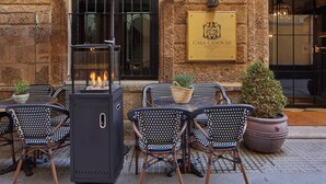 An outdoor seating area with a grill, chairs, and a potted plant.