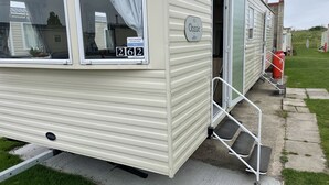 Ein Wohnmobil mit Schiebetür, einer kleinen Stufe davor und einem Hinweisschild an der Tür.