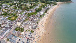 An aerial view of a coastal town with a beach, residential buildings, and a parking area. - Ivydene - Beautiful Cottage Stone Throw From Beach Wonderful Sea Views (Saundersfoot)