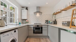 A compact kitchen with a washing machine, a stove, and a dishwasher. - Ivydene - Beautiful Cottage Stone Throw From Beach Wonderful Sea Views (Saundersfoot)
