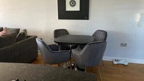 A room with a dining table, four chairs, a sofa, and a framed artwork on the wall. - Beautiful Sea view apartment in Carlyon Bay (Carlyon Bay)