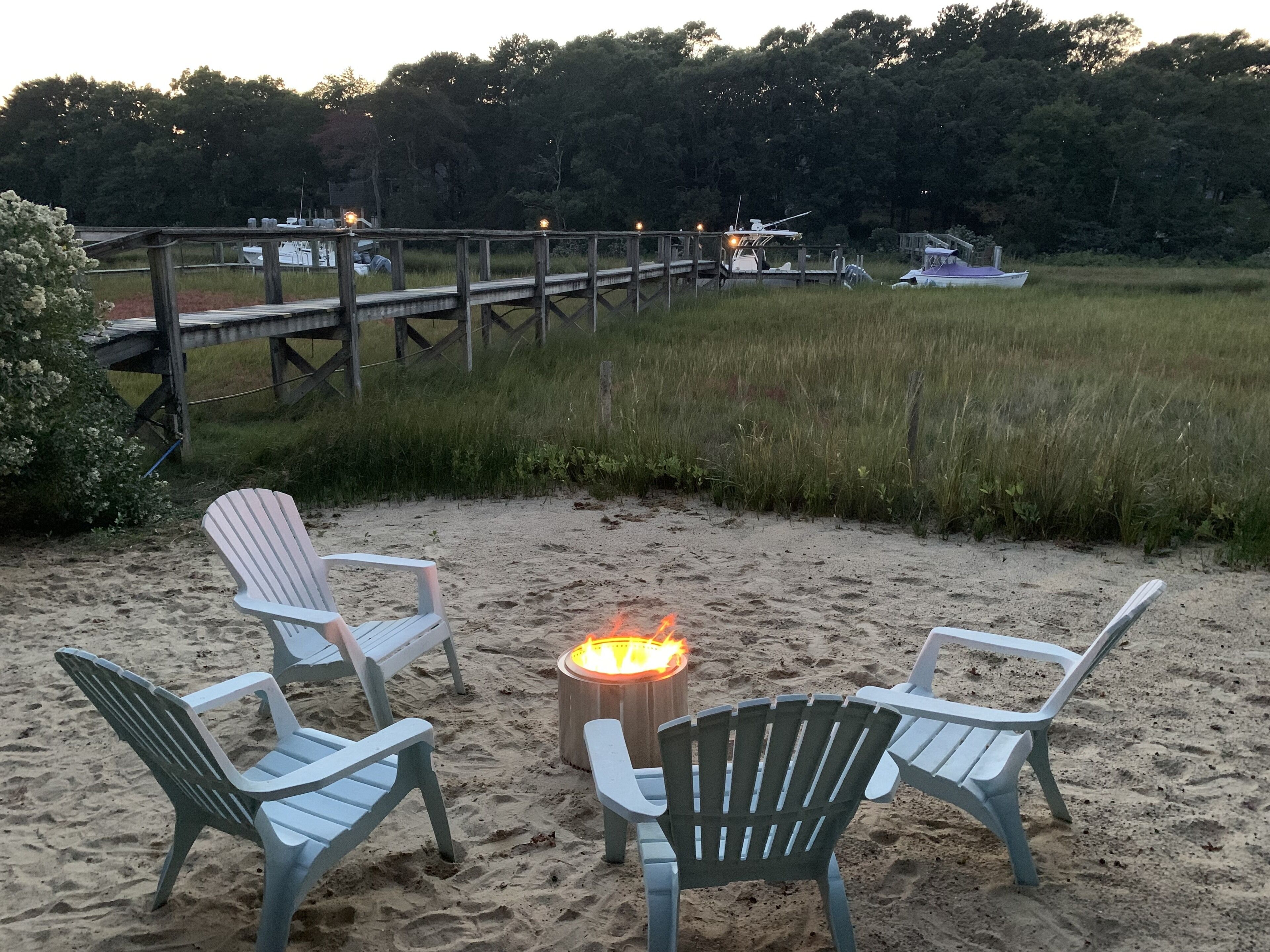 Un espace de détente aménagé sur la plage, avec deux fauteuils Adirondack et un foyer.