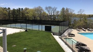 Tennisbane, swimmingpool og en græsplæne med liggestole.