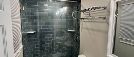 Une salle de bain compacte dotée d’une douche à parois de verre, de toilettes et d’un lavabo avec un plan de travail en marbre.