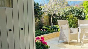 A patio area with wicker furniture, a large umbrella, and potted plants. - Stunning Interior designed cottage (Chipping Campden)