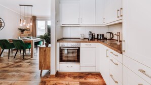 Una cocina moderna con armarios blancos, horno integrado y encimera de madera.