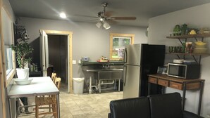 Cocina compacta con refrigerador, microondas, lavamanos y comedor con sillas.