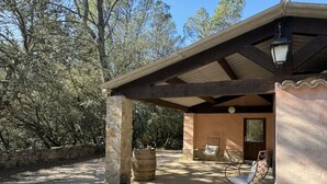 A covered outdoor seating area with stone pillars, a wooden pergola, and a stone barrel. - Silence in the Green Provence (Carcès)