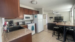 A compact kitchen with a microwave, stove, sink, and a small dining area with stools. - Cozy Oro Valley Retreat, close to Golf, Trails & Fine Dining-Dog Friendly (Tucson)