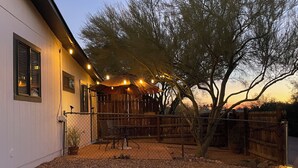 A covered outdoor seating area with a wooden fence, a potted plant, and string lights. - Cozy Oro Valley Retreat, close to Golf, Trails & Fine Dining-Dog Friendly (Tucson)