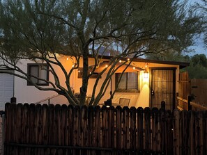 A wooden house with a fenced yard, string lights, and a door with a window. - Cozy Oro Valley Retreat, close to Golf, Trails & Fine Dining-Dog Friendly (Tucson)