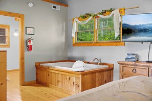 Ein Badezimmer aus Holz mit einer Badewanne, einem Fenster mit Seeblick und einem Feuerlöscher.