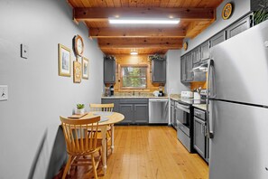 Eine moderne Küche mit Holzbalken, Edelstahlgeräten und einem Essbereich mit Holztisch und Stühlen.