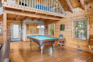 Un intérieur en bois avec une table de billard, un canapé et un balcon.