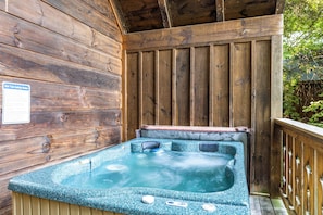 A hot tub with a wooden deck and a safety sign on the wall.