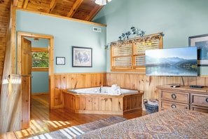 A wooden interior with a large bathtub, a television, and a framed picture on the wall.