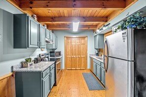 A compact kitchen with wooden cabinets, a stainless steel refrigerator, and a microwave.