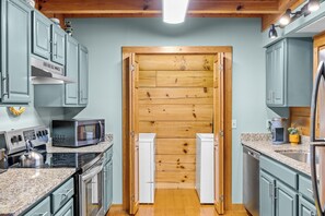 Una cocina con gabinetes azul claro, una puerta de madera, electrodomésticos de acero inoxidable y una encimera de granito.