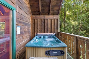 A wooden cabin with a hot tub on a deck.