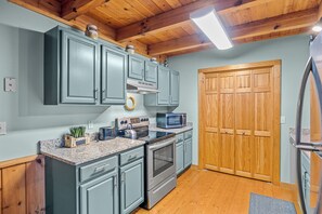 Una cocina con armarios grises, un microondas, una estufa y una puerta de madera.