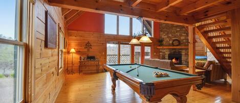 Relax by the fireplace or challenge friends to a game of pool in this inviting room with a staircase leading to an upper level.