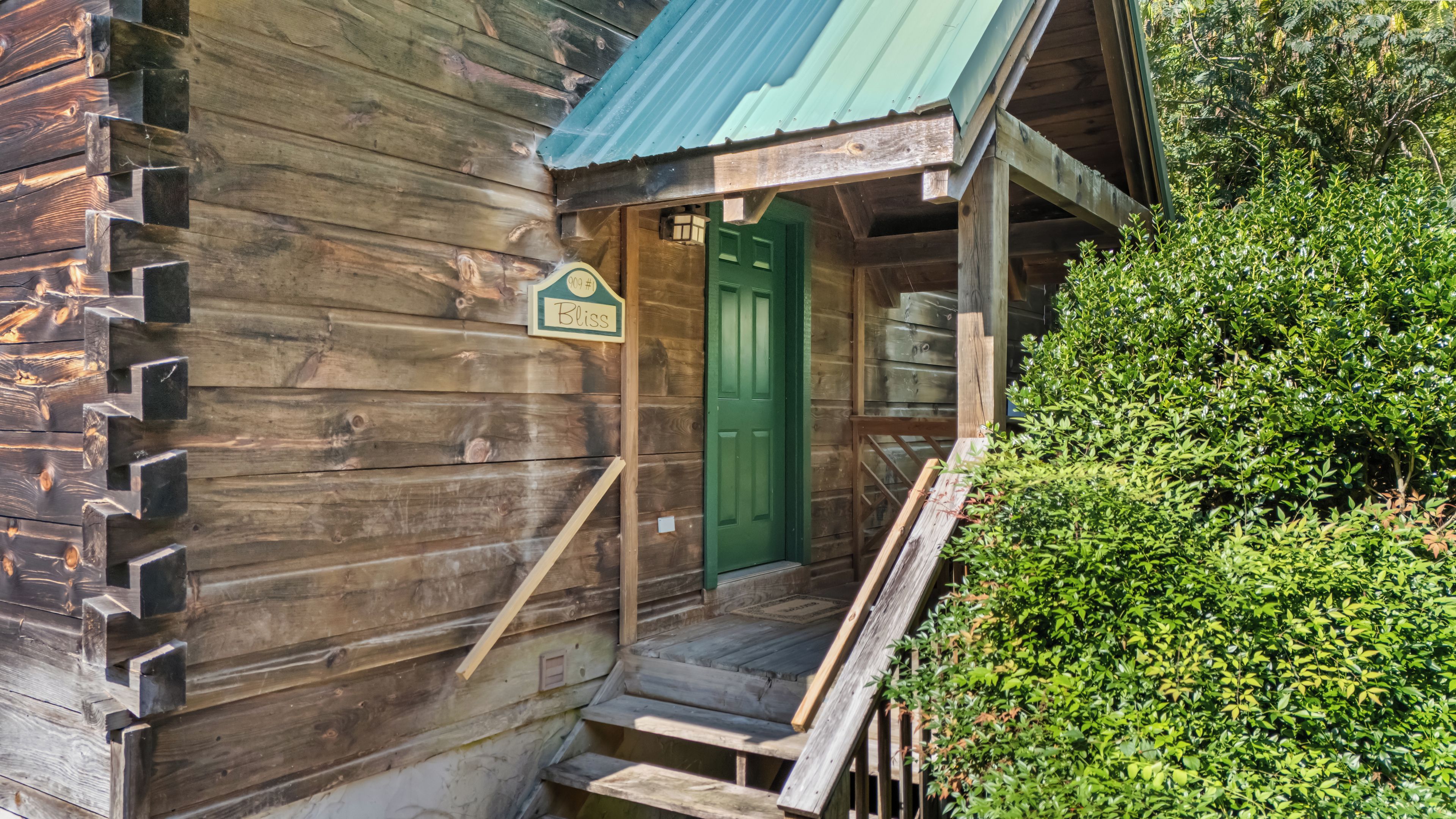 A wooden building with a green door, a sign reading 'Biss', and a wooden staircase leading to the entrance.