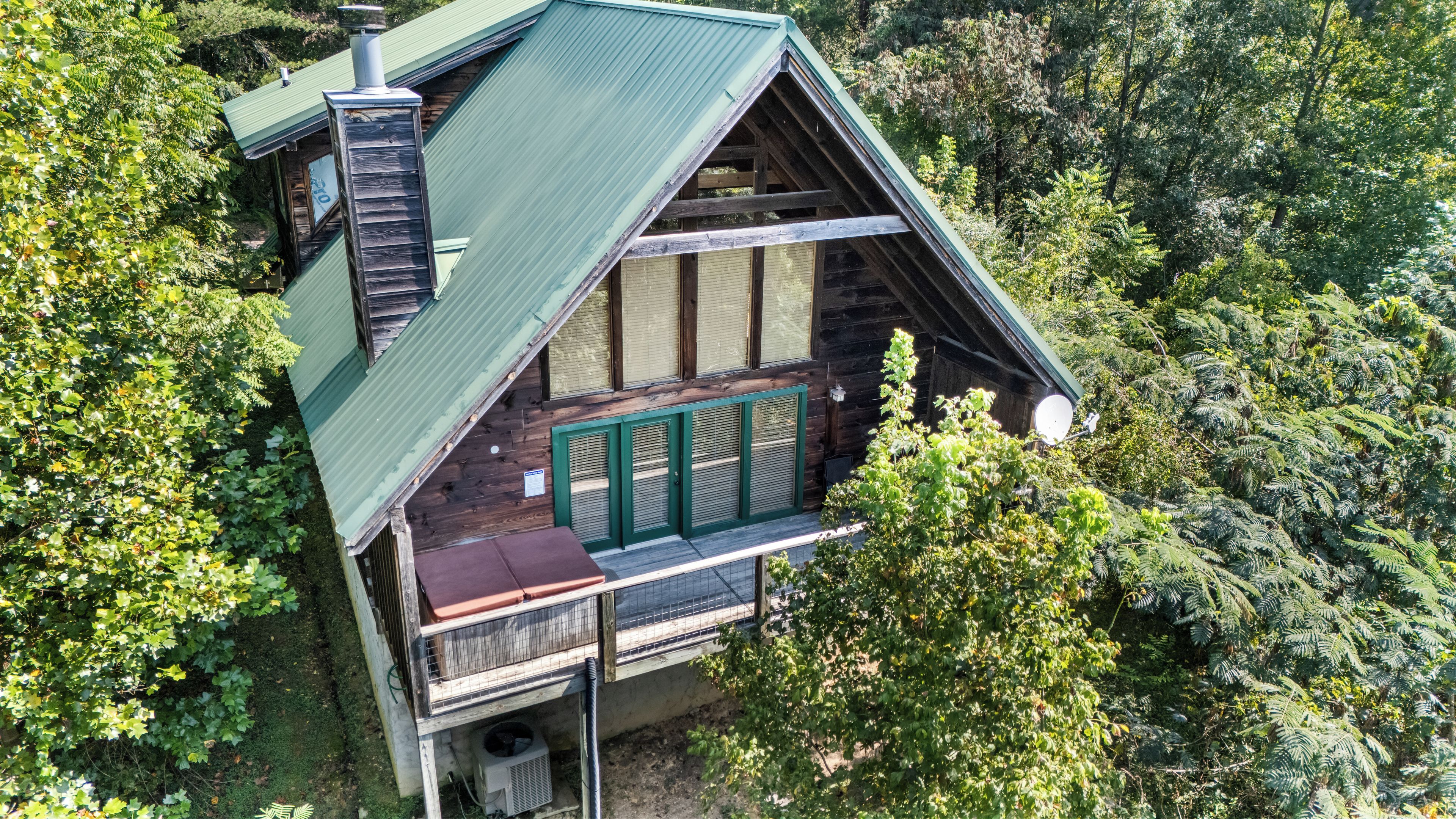 Een chalet met schuin dak, een balkon met groene reling en een schoorsteen.