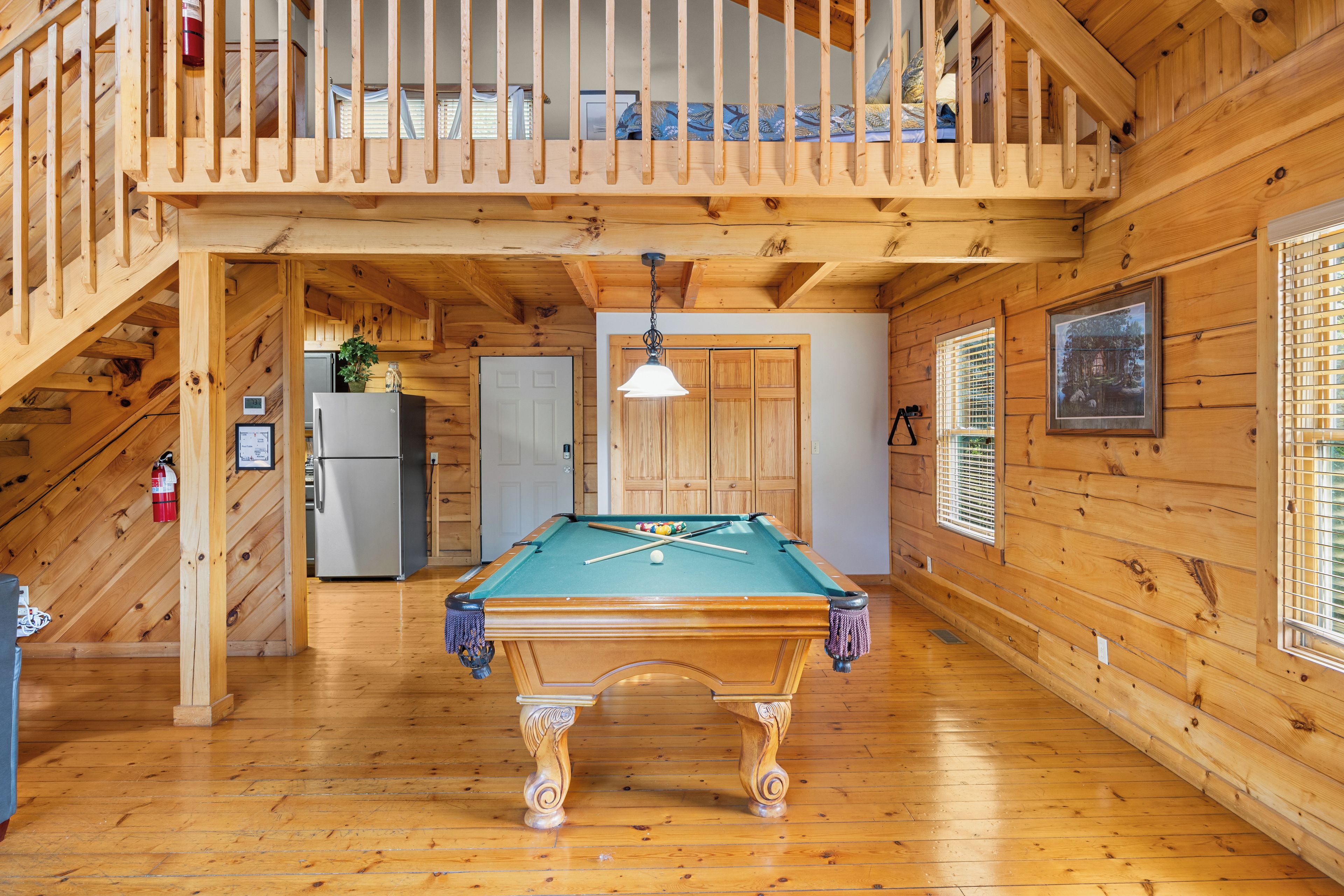 Un interno in legno con tavolo da biliardo, un balcone e una scala.