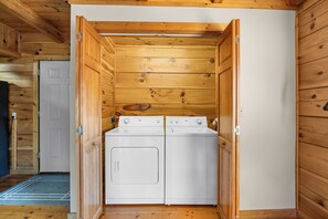 A laundry room with a washer and dryer, wooden walls, and a white door. - Bliss- Beautiful Mountain Views, Pool Table, Hot Tub, Free attraction tickets daily (Gatlinburg)