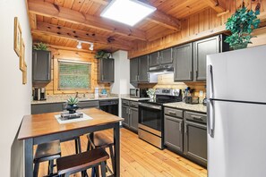 A kitchen with wooden cabinets, a stainless steel refrigerator, and a wooden dining table with chairs.