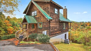 A rustic log cabin with a green roof, a porch, and a chimney. - Mystic- Situated in a very private wooded setting with great mountain views!! (Gatlinburg)