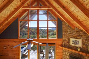 A wooden interior with large windows, a stone wall, and a fireplace.