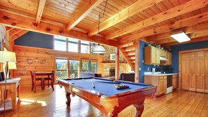 A wooden-floored room with a pool table, a dining area, and a kitchen. - Mystic- Situated in a very private wooded setting with great mountain views!! (Gatlinburg)