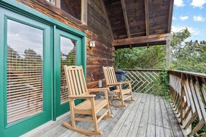 A wooden deck with two rocking chairs and a green door. - Enchanted - beautiful view for miles, private and peaceful. (Gatlinburg)