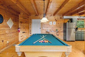 A pool table in a wooden room with a kitchen area. - Enchanted - beautiful view for miles, private and peaceful. (Gatlinburg)