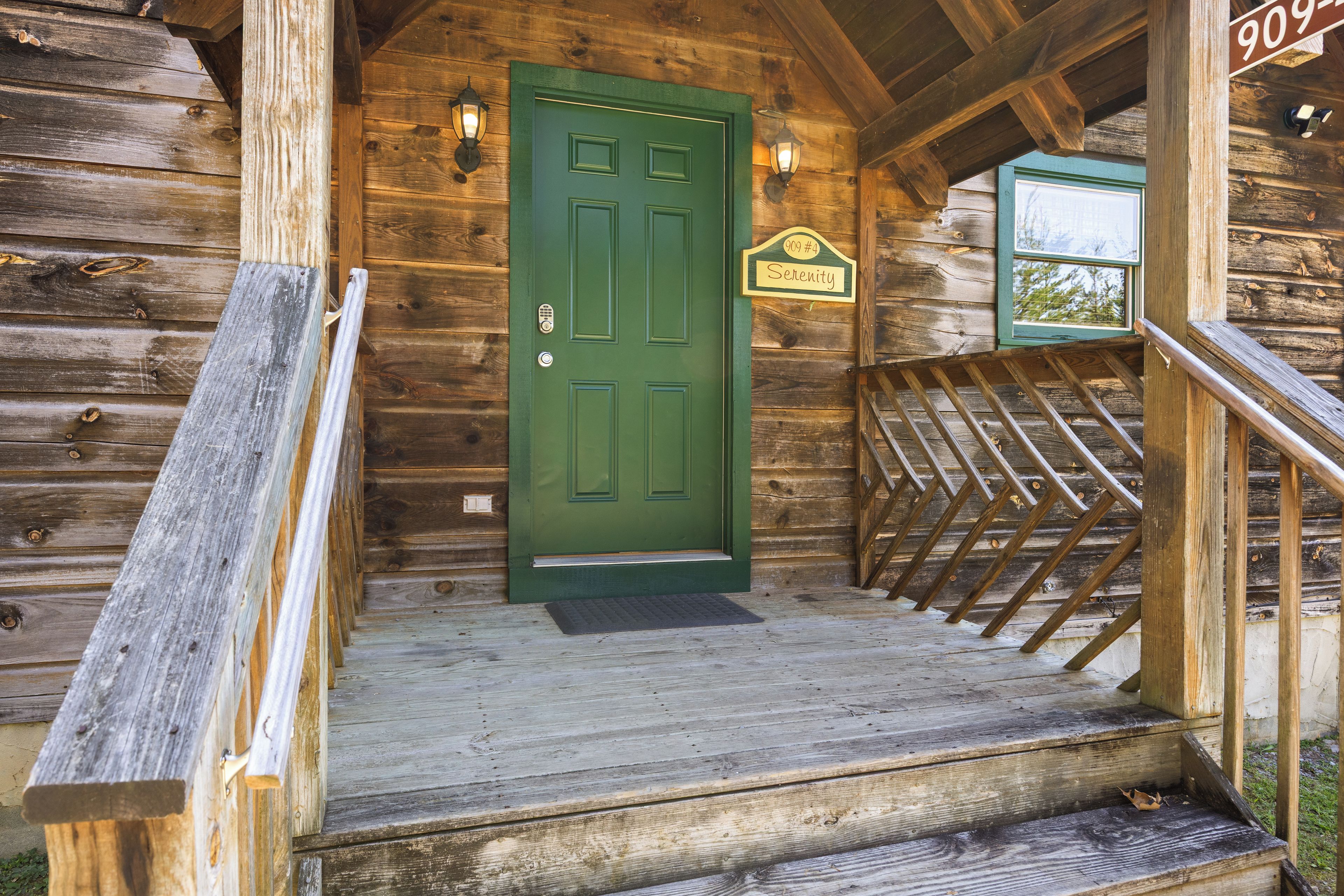 Une cabane en bois avec une porte verte, une boîte aux lettres et un escalier menant à l’entrée.