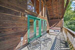 A wooden deck with a covered area, a green door, and outdoor furniture. - Serenity- Find your solitude at the 1 bedroom cabin! (Gatlinburg)
