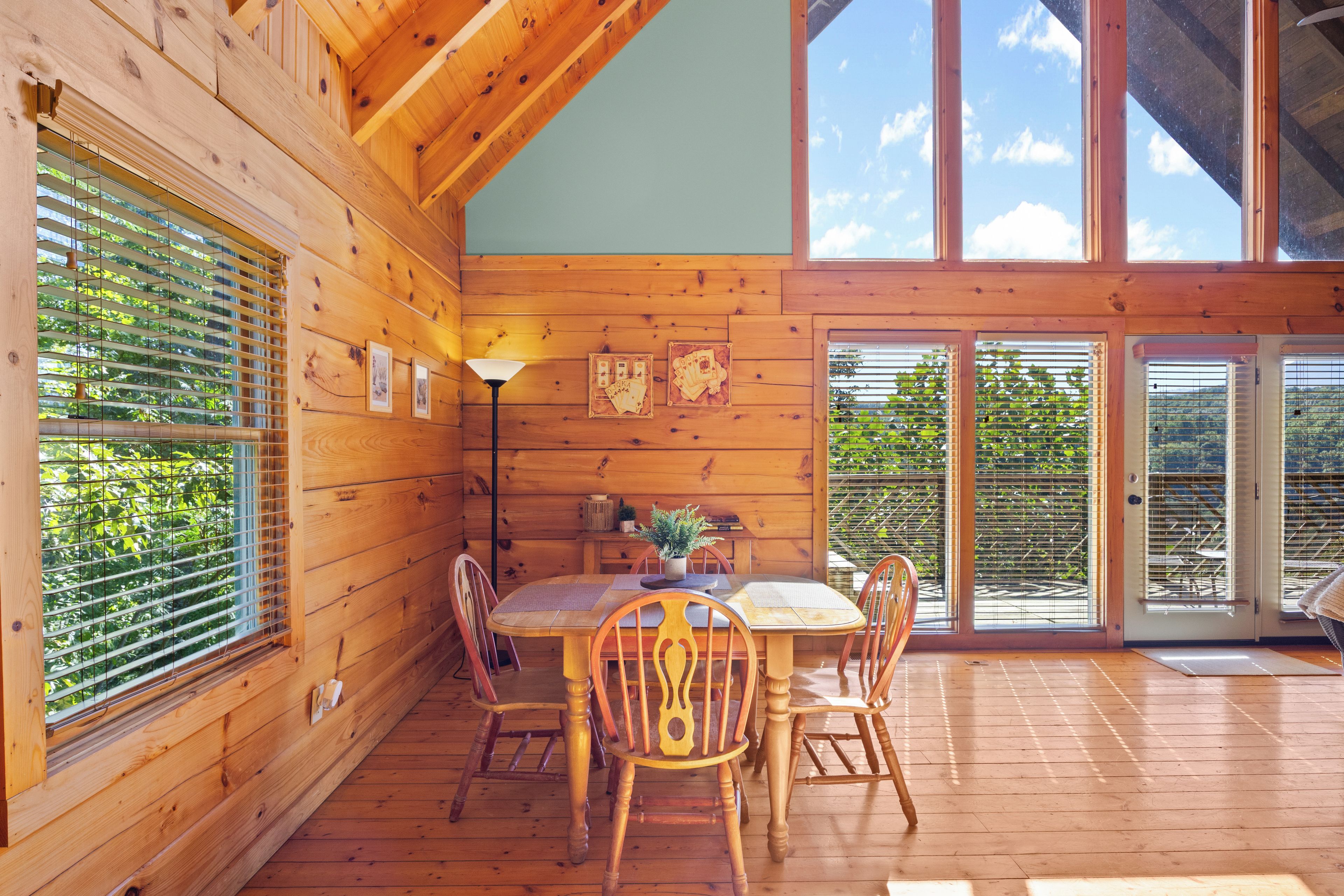 Un intérieur en bois avec une table à manger, des chaises et une lampe.