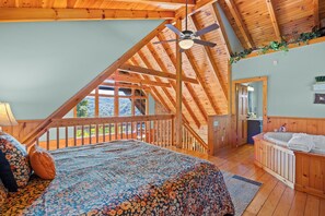 Un dormitorio con una cama grande, ventilador de techo y vista al exterior.