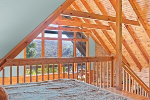 A room with a sloped wooden ceiling, large windows, and a view of greenery outside. - Serenity- Find your solitude at the 1 bedroom cabin! (Gatlinburg)